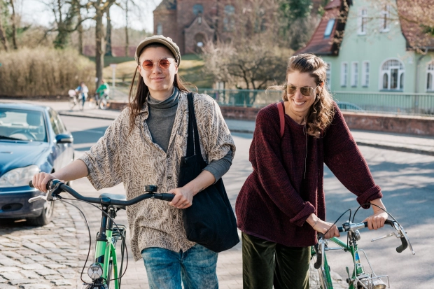 a lesbian couple walking city street sunshine bicycles way