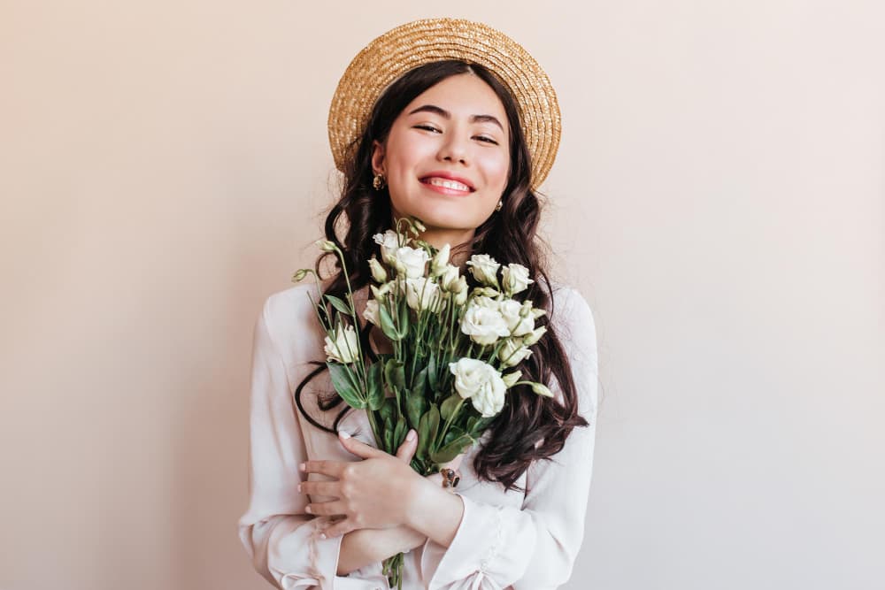 cheerful asian girl straw hat holding flowers young woman with white eustomas expressing happiness